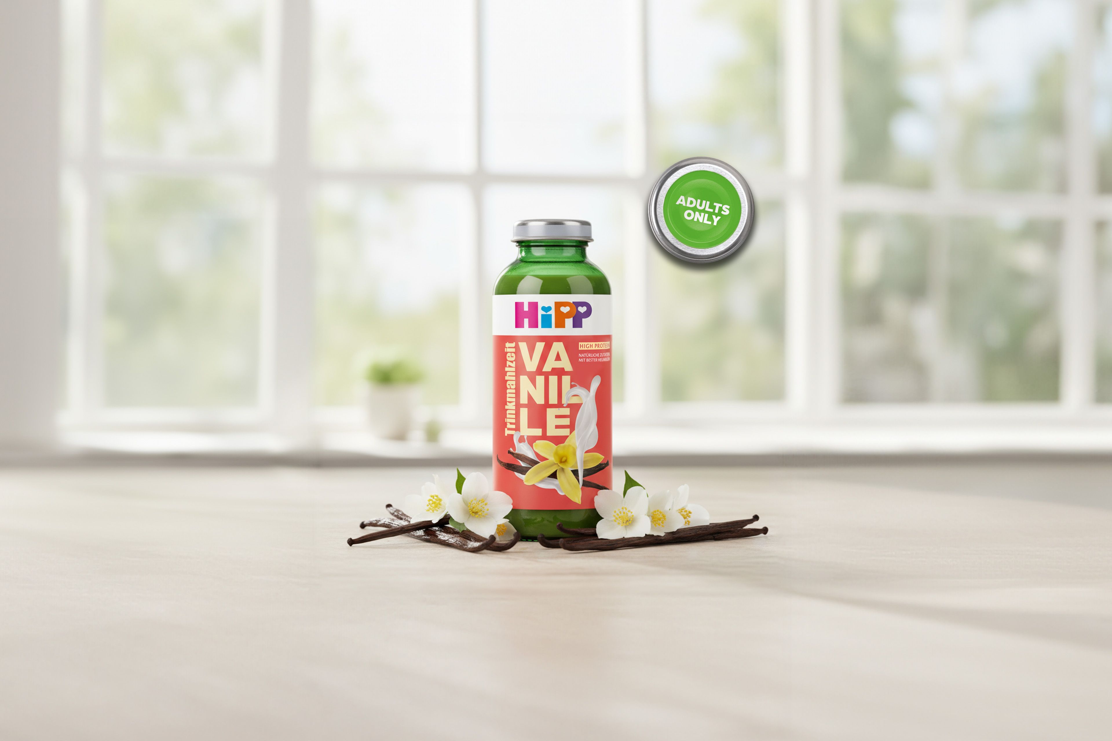 HiPP Trinkmahlzeit Vanille in grüner Glasflasche mit Vanilleblüte und Vanilleschoten auf dem Etikett