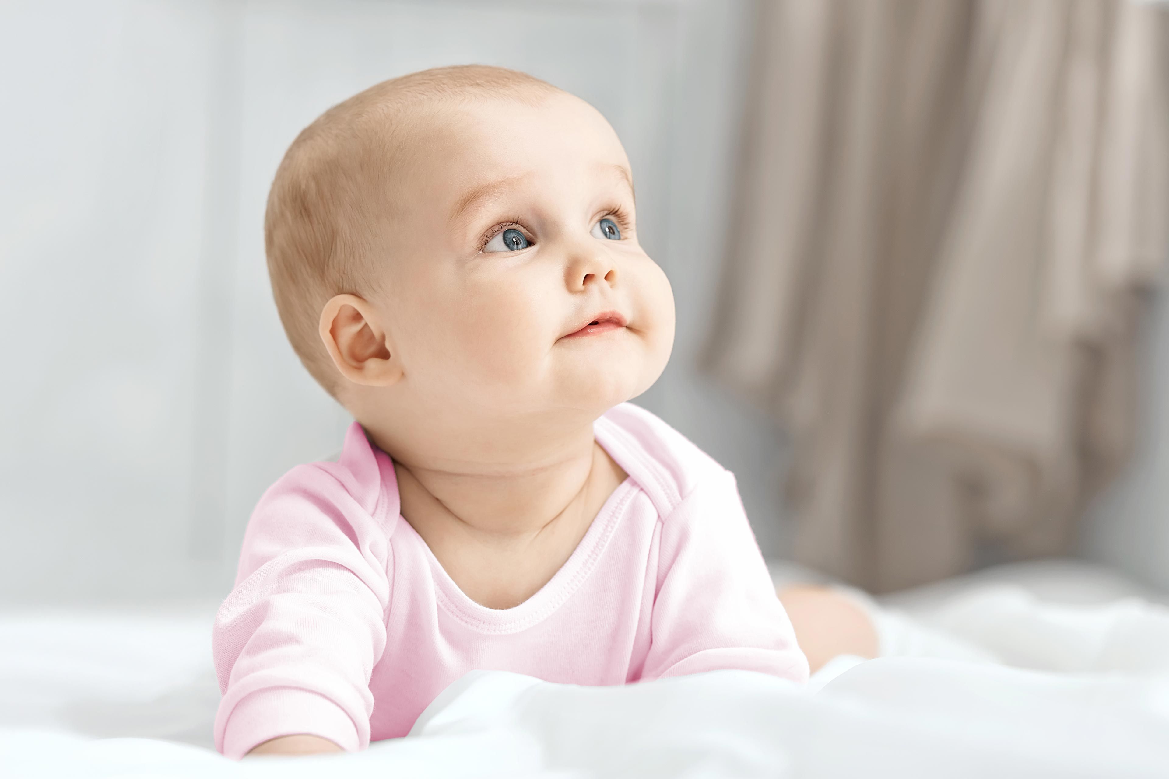 Baby sitzt vor einem weißen Hintergrund mit einem weißen Stoffzelt