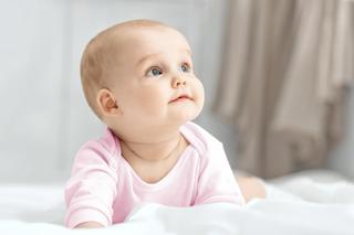 Baby sitzt vor einem weißen Hintergrund mit einem weißen Stoffzelt