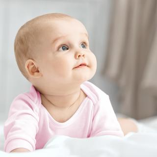 Baby sitzt vor einem weißen Hintergrund mit einem weißen Stoffzelt