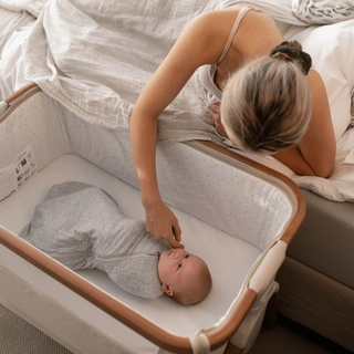 Mum attending to baby in a next to me crib