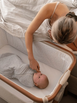 Mum attending to baby in a next to me crib