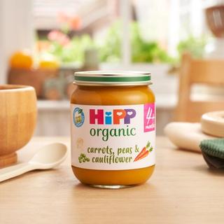HiPP Organic Carrots, Peas & Cauliflower jar on a dining table next to a bowl and spoon