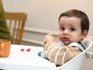 Baby playing with food in highchair