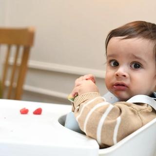 Baby playing with food in highchair