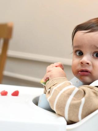 Baby playing with food in highchair
