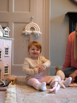 Mum and daughter playing with dolls and dollhouse