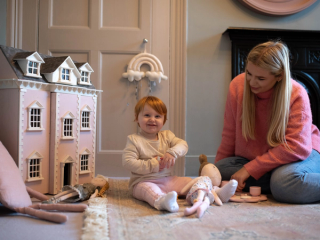Mum and daughter playing with dolls and dollhouse
