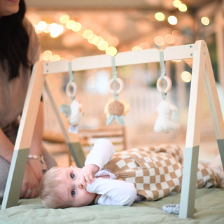 Baby on a play mat chewing on his fingers