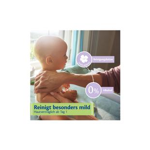 Ein Baby sitzt auf einem Tisch, eine Hand hält es sanft am Oberkörper, daneben sind Textfelder mit den Worten 'Reinigungslotion', '0% Alkohol' und 'Reinigt besonders mild Hautverträglich ab Tag 1'