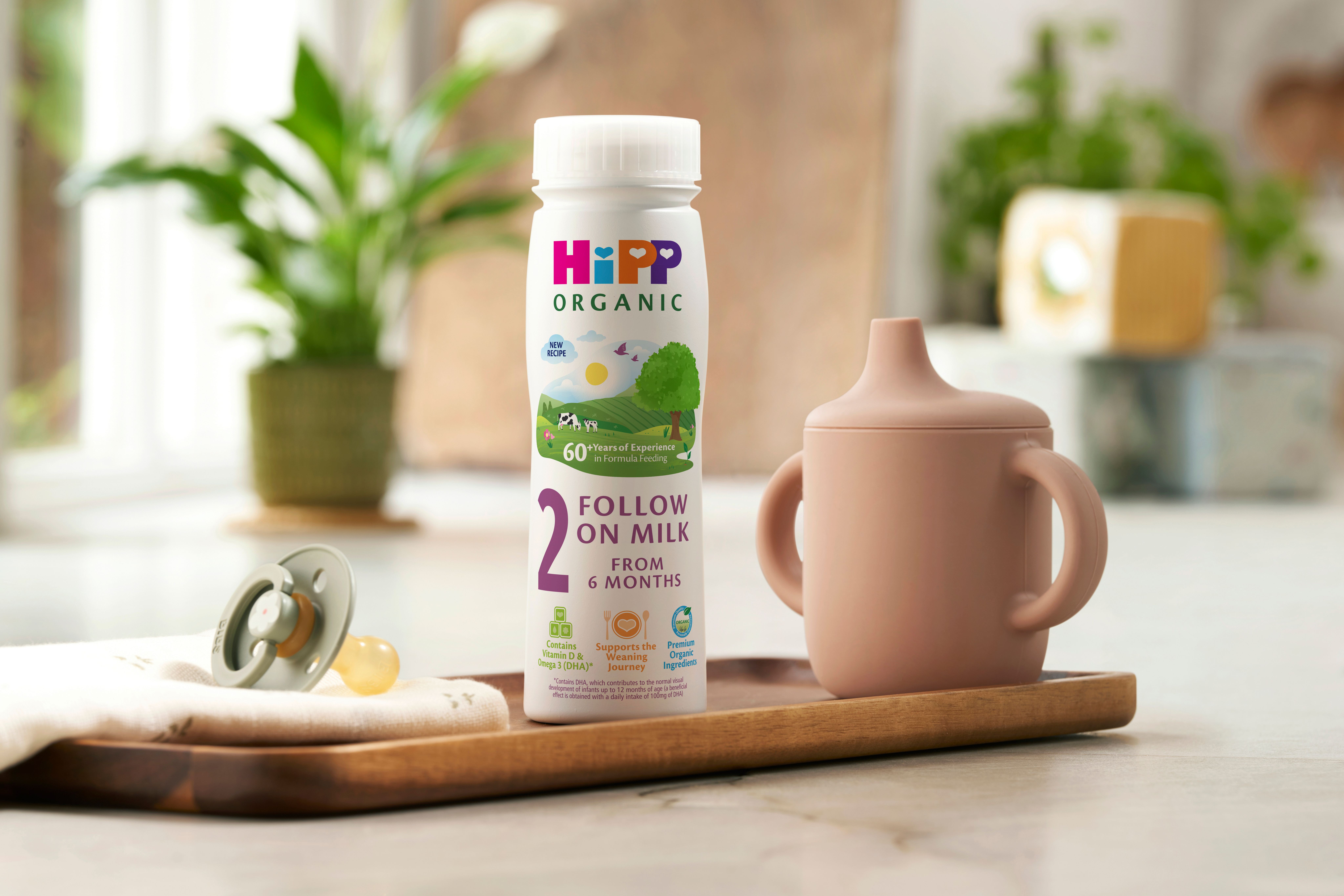 HiPP Organic follow on milk ready to feed on a wooden tray next to a beaker and dummy