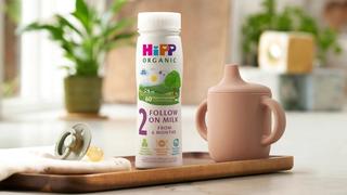 HiPP Organic follow on milk ready to feed on a wooden tray next to a beaker and dummy