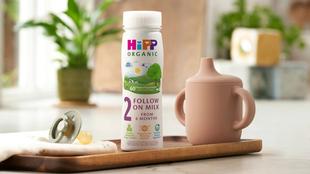 HiPP Organic follow on milk ready to feed on a wooden tray next to a beaker and dummy