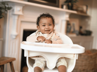 Baby sat in high chair smiling
