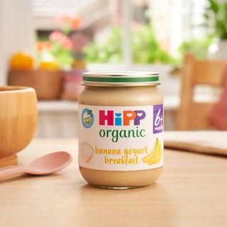 HiPP Organic Banana Yogurt Breakfast jar on a dining table next to a bowl and spoon