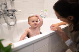 Toddler in a seat in the bath with mum
