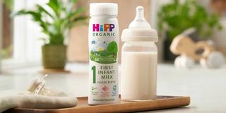 first infant milk ready to feed bottle next to a milk bottle on a kitchen worktop