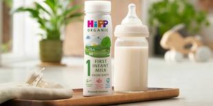 first infant milk ready to feed bottle next to a milk bottle on a kitchen worktop