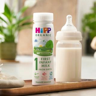 first infant milk ready to feed bottle next to a milk bottle on a kitchen worktop