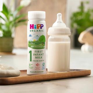 first infant milk ready to feed bottle next to a milk bottle on a kitchen worktop