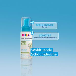 Flasche mit Schaumdusche von HiPP vor blauem Hintergrund mit Texten 'Beruhigende Formel', 'Schützt die natürliche pH-Hautbalance' und 'Wohltuende Schaumdusche'