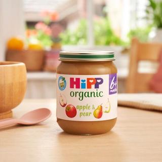 HiPP Organic Apple & Pear jar on a dining table next to a bowl and spoon