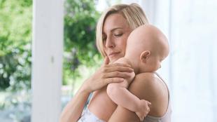 Eine Frau, die ein Baby an sich drückt, beide scheinen sich in einem ruhigen und intimen Moment zu befinden.