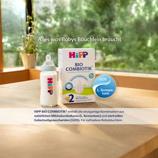 Packung HiPP Bio Combiotik 2 Babynahrung steht auf einem Holztisch vor einem Fenster mit Pflanzen im Hintergrund