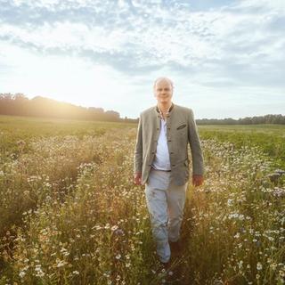 Stefan Hipp walking in a field with sunshine behind him