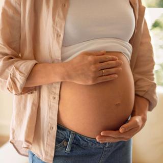 Eine Person, die schwanger ist, berührt sanft ihren Bauch.