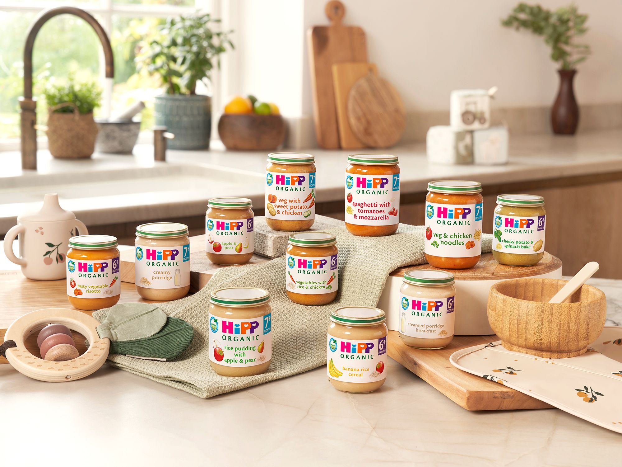 Selection of HiPP Organic baby food jars arranged on a bright kitchen worktop with baby tableware