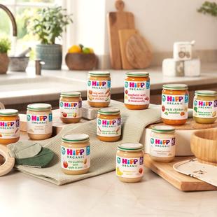 Selection of HiPP Organic baby food jars arranged on a bright kitchen worktop with baby tableware