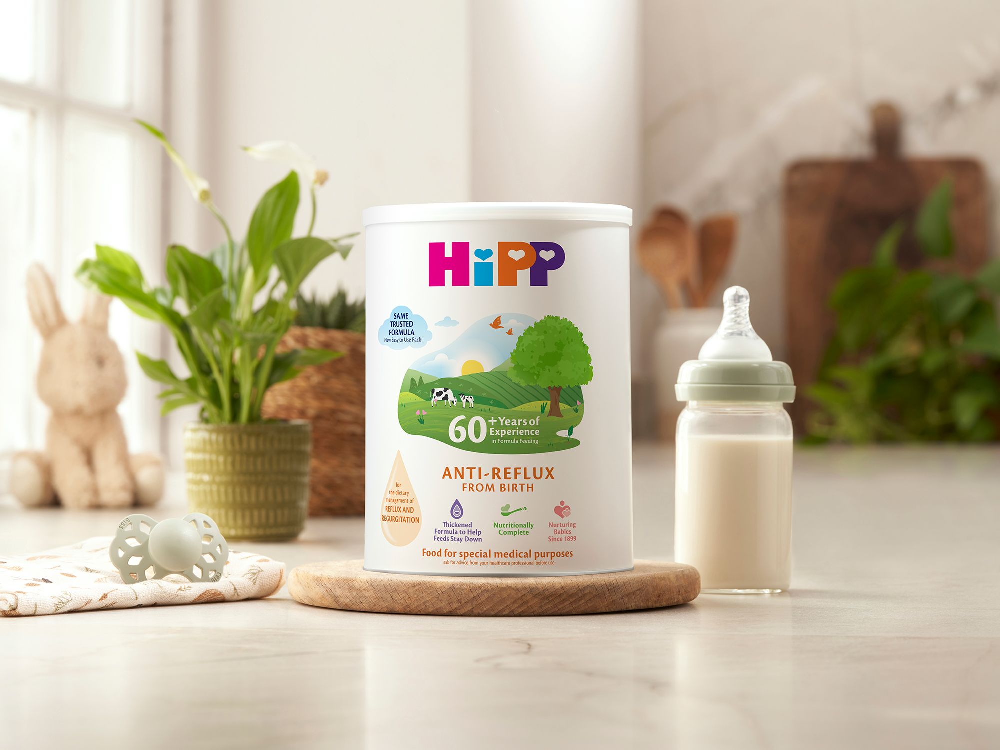HiPP Organic anti reflux milk powder tin next to milk bottle on a kitchen worktop