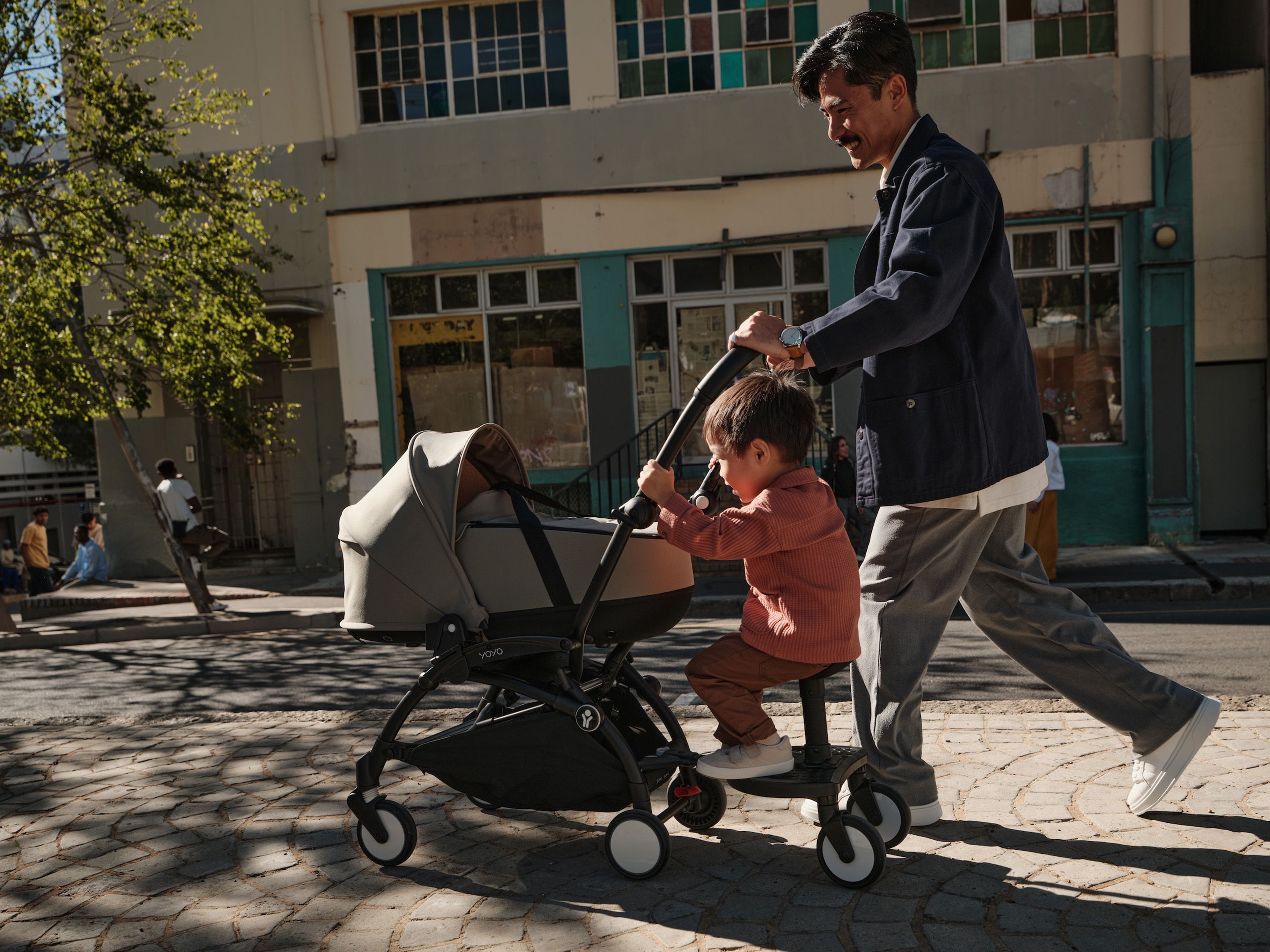 Vater läuft mit kleinem Kind und Kinderwagen