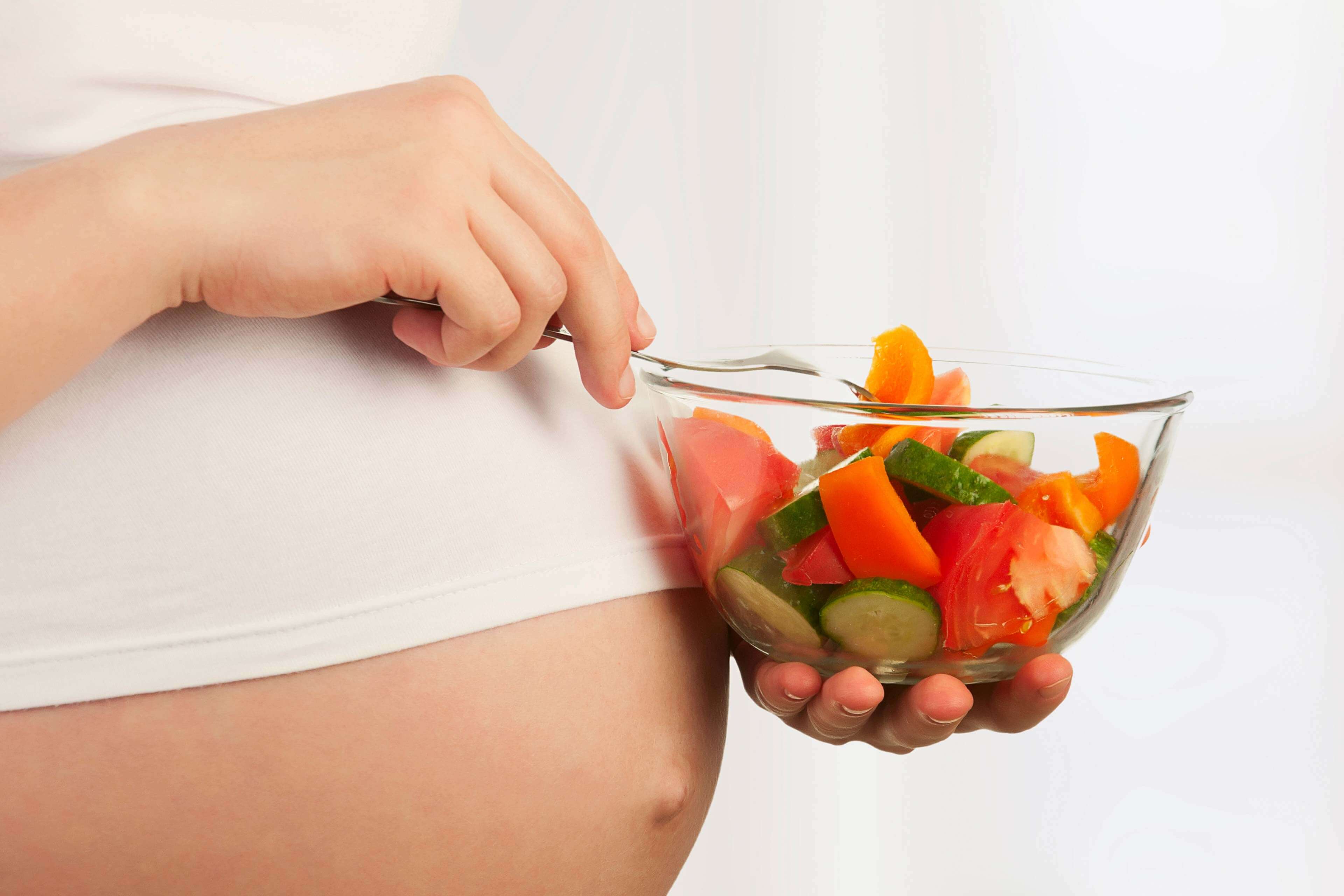 Eine Person mit einem Glas frischem Gemüse in der Hand, das die Bedeutung einer ausgewogenen Ernährung während der Schwangerschaft unterstreicht.
