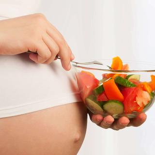 Eine Person mit einem Glas frischem Gemüse in der Hand, das die Bedeutung einer ausgewogenen Ernährung während der Schwangerschaft unterstreicht.