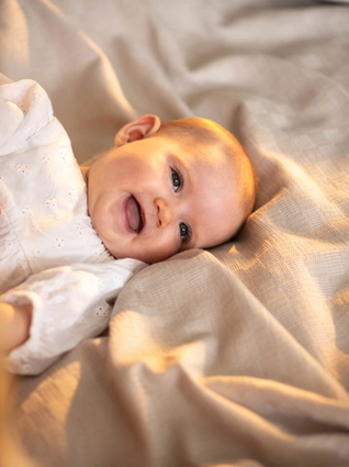 Baby lying on bed smiling