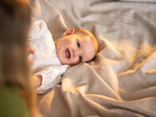 Baby lying on bed smiling