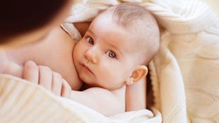 Ein zärtlicher Moment zwischen einer Mutter und ihrem Baby, das mit neugierigem Blick direkt in die Kamera blickt.