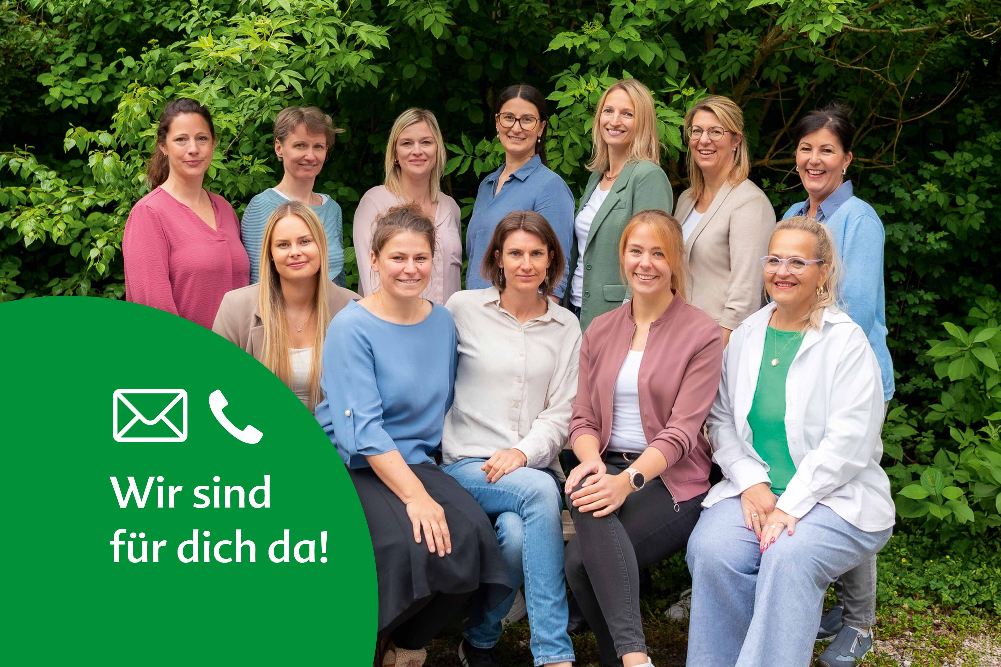 Das HiPP Elternservice-Team lächelt gemeinsam vor grünen Büschen in die Kamera.