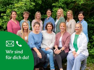 Das HiPP Elternservice-Team lächelt gemeinsam vor grünen Büschen in die Kamera.