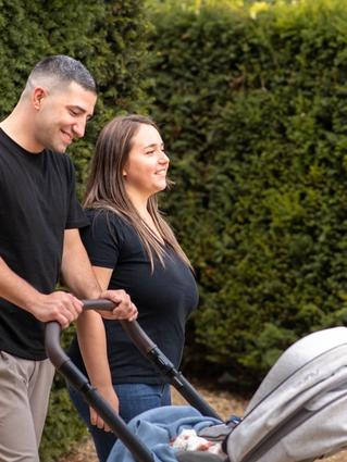 Dad pushing stroller looking down at baby whilst mum is smiling looking into the distance.