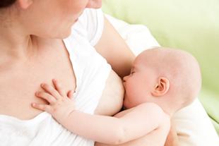Die Brust einer Mutter, an der ein Baby gestillt wird.