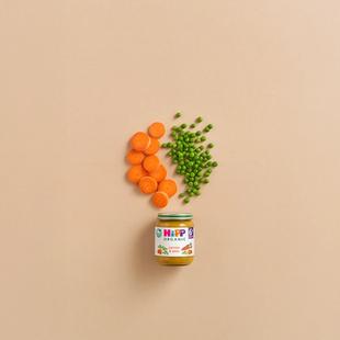 HiPP Organic Carrots & Peas baby food jar with sliced carrots and peas arranged above on a neutral background