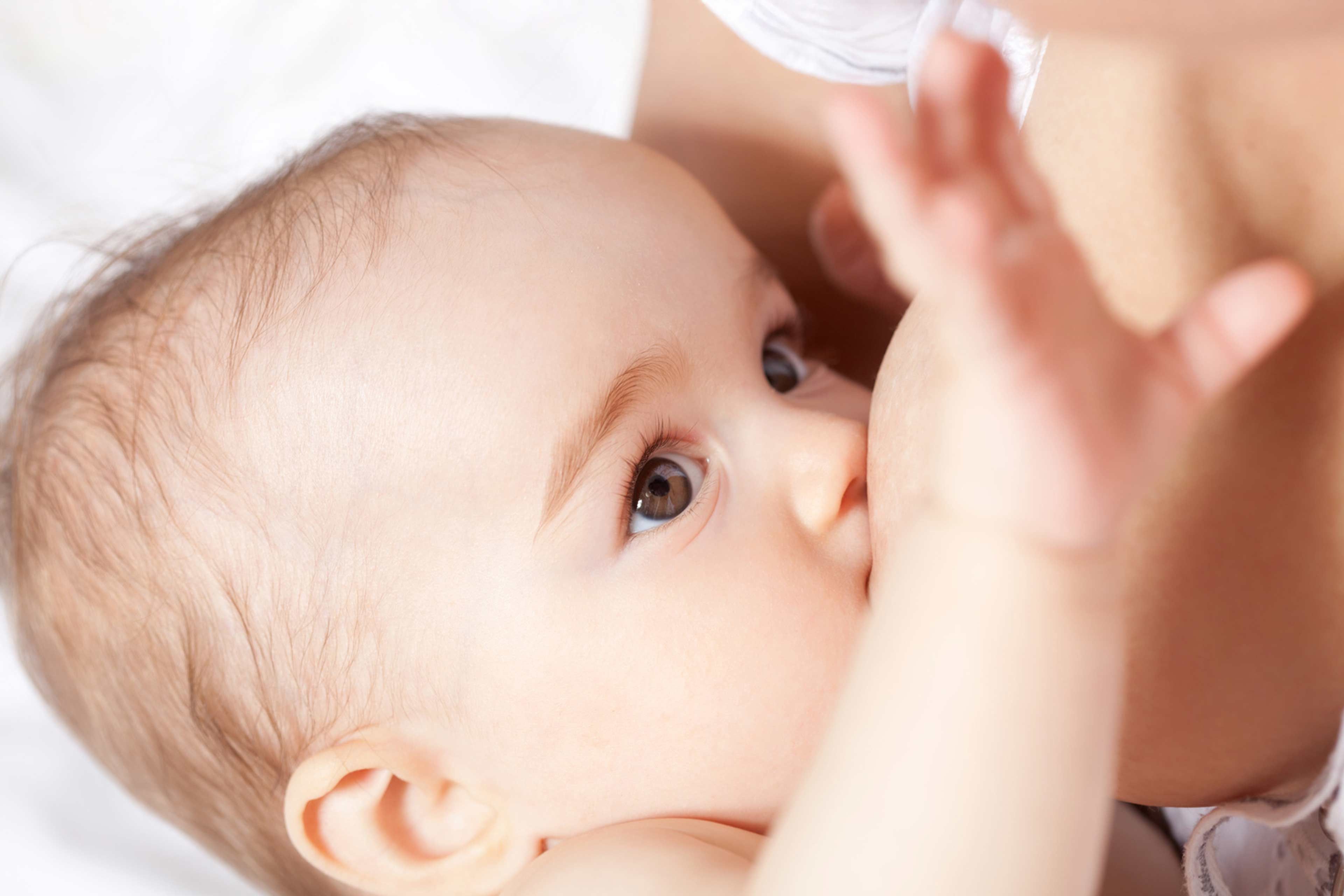 Nahaufnahme eines Babygesichts mit Schwerpunkt auf den Augen und dem Akt des Stillens.