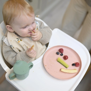 Baby eating toast and fruit in a highchair