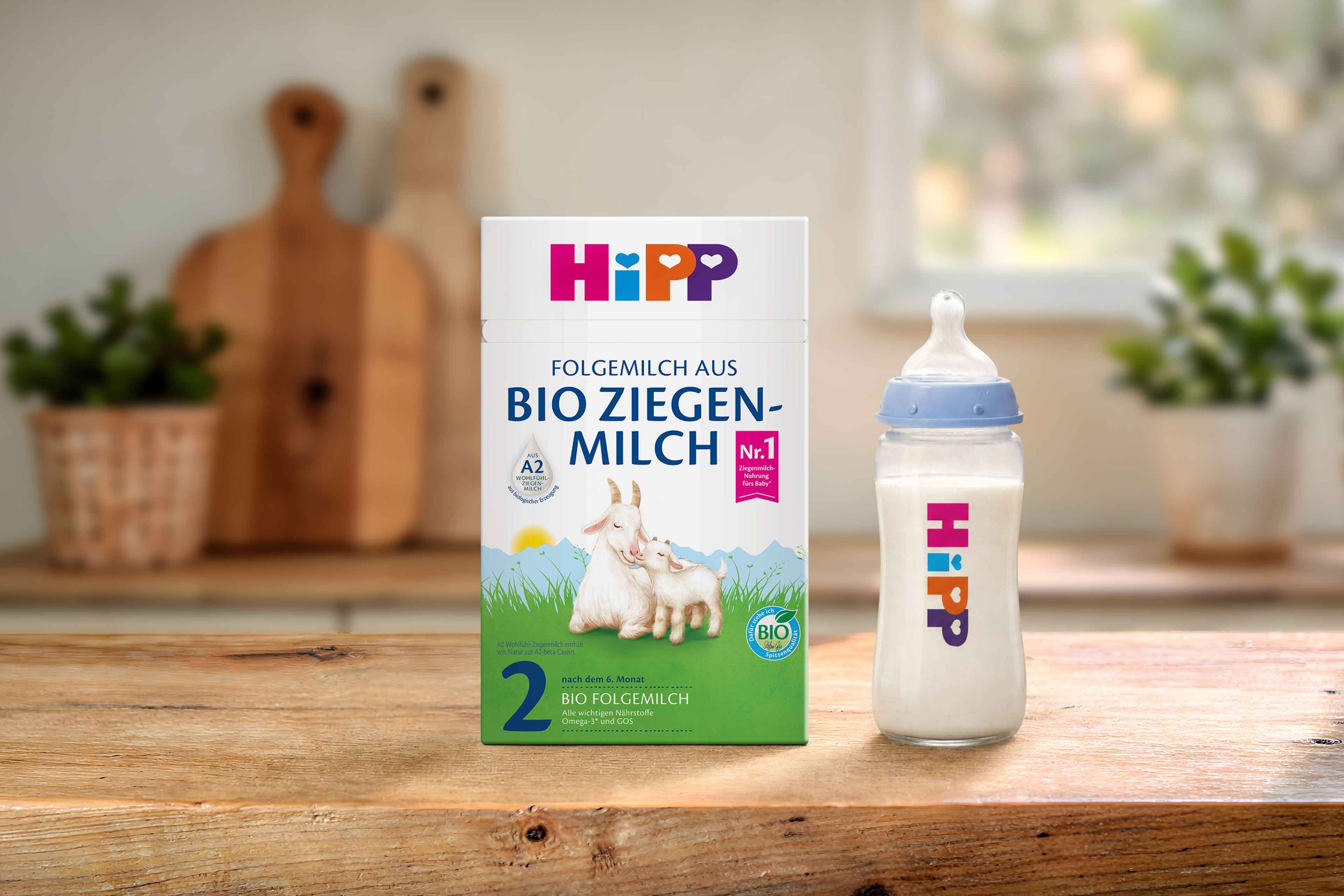 HiPP 2 Folgemilch aus Bio Ziegenmilch Packung neben gefüllter Babyflasche auf Holztisch in heller Küche