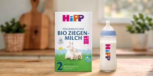 HiPP 2 Folgemilch aus Bio Ziegenmilch Packung neben gefüllter Babyflasche auf Holztisch in heller Küche