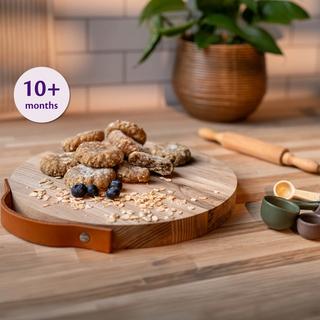 Baby-friendly banana and blueberry chewy biscuits on a wooden plate with sliced banana and strawberries.