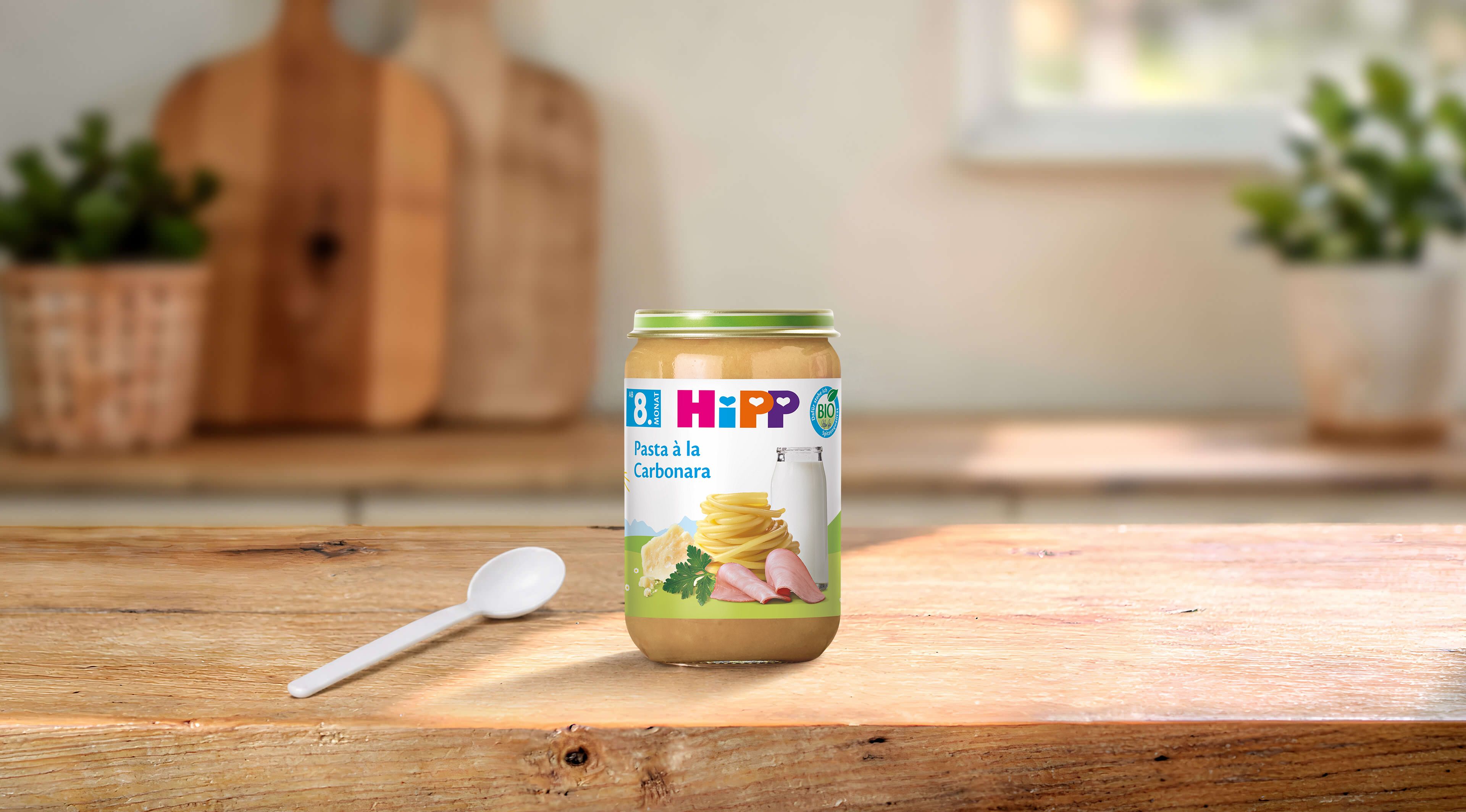 HiPP Bio Pasta à la Carbonara im 220-g-Gläschen mit Löffel auf einem Holztisch